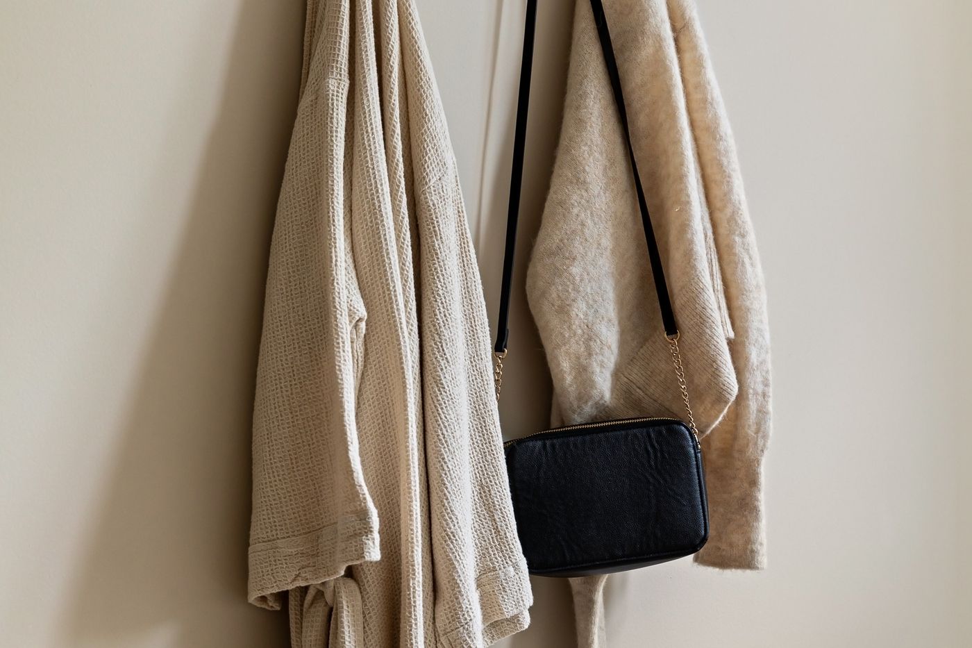 Hakenleiste an der Wand mit Mantel und Tasche