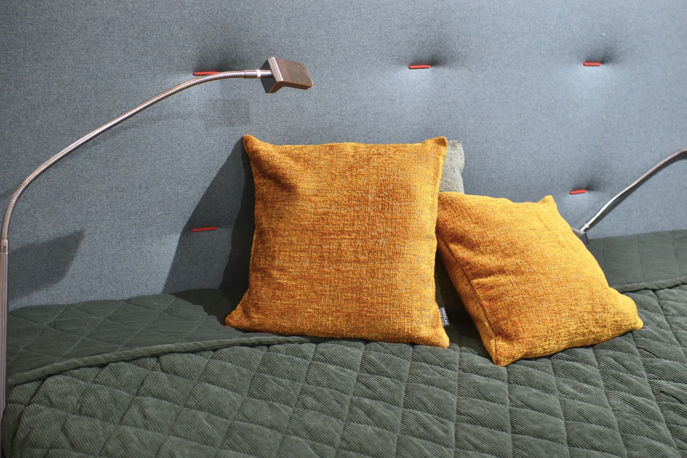 Senfgelbe Kissen auf einer moosgrünen Tagesdecke